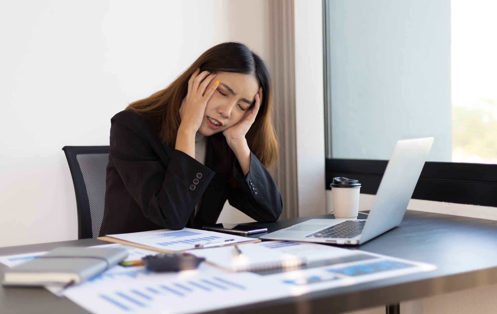 Overworked businesswoman in the office has stress and has a very uncomfortable headache.